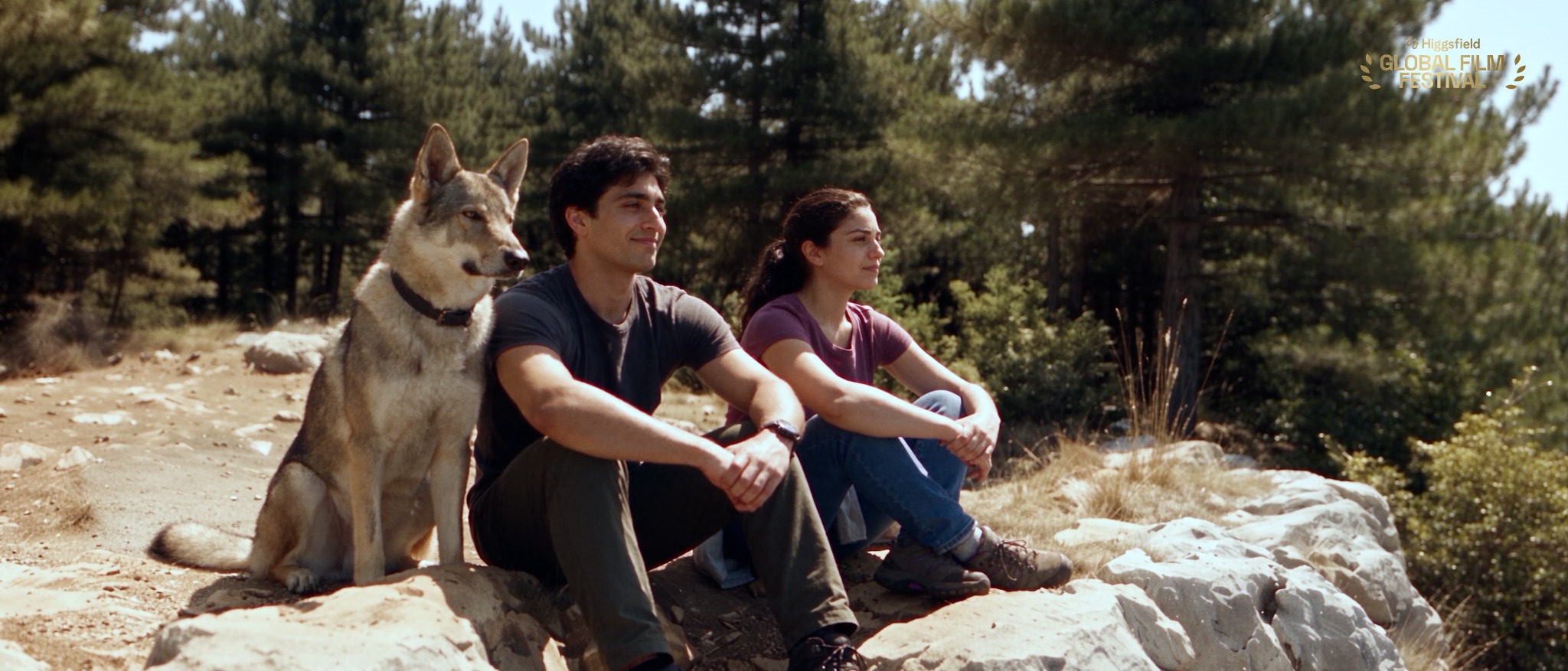 Noah, Talia and Koda sitting together on a mountain